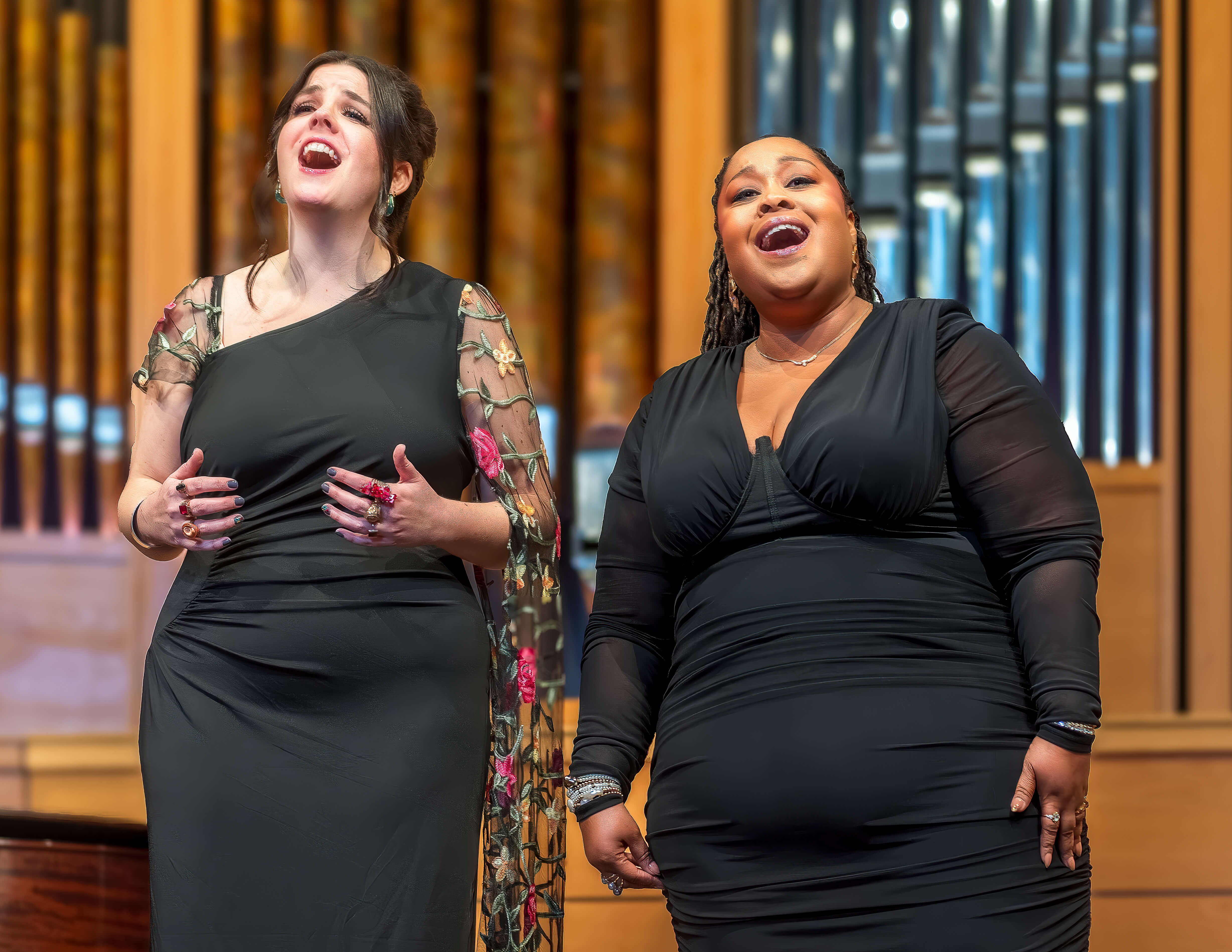 Two singers in front of a pipe organ.